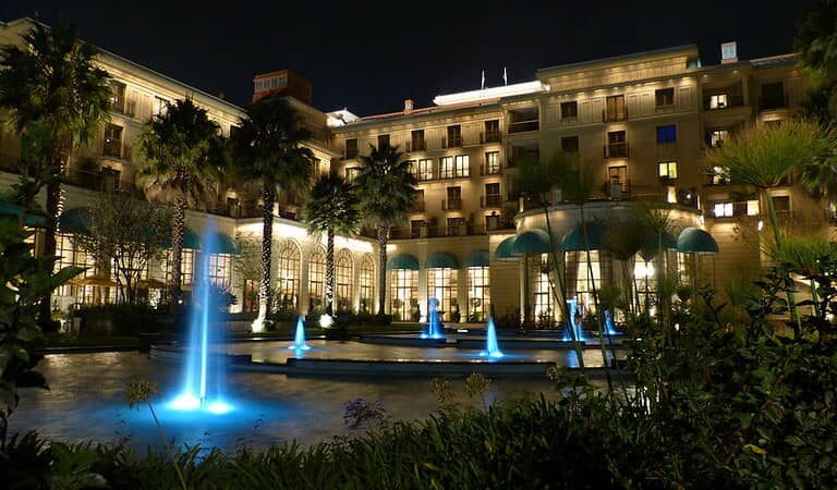 The hotel illuminated at night, surrounded by fountains, creating a captivating scene.
