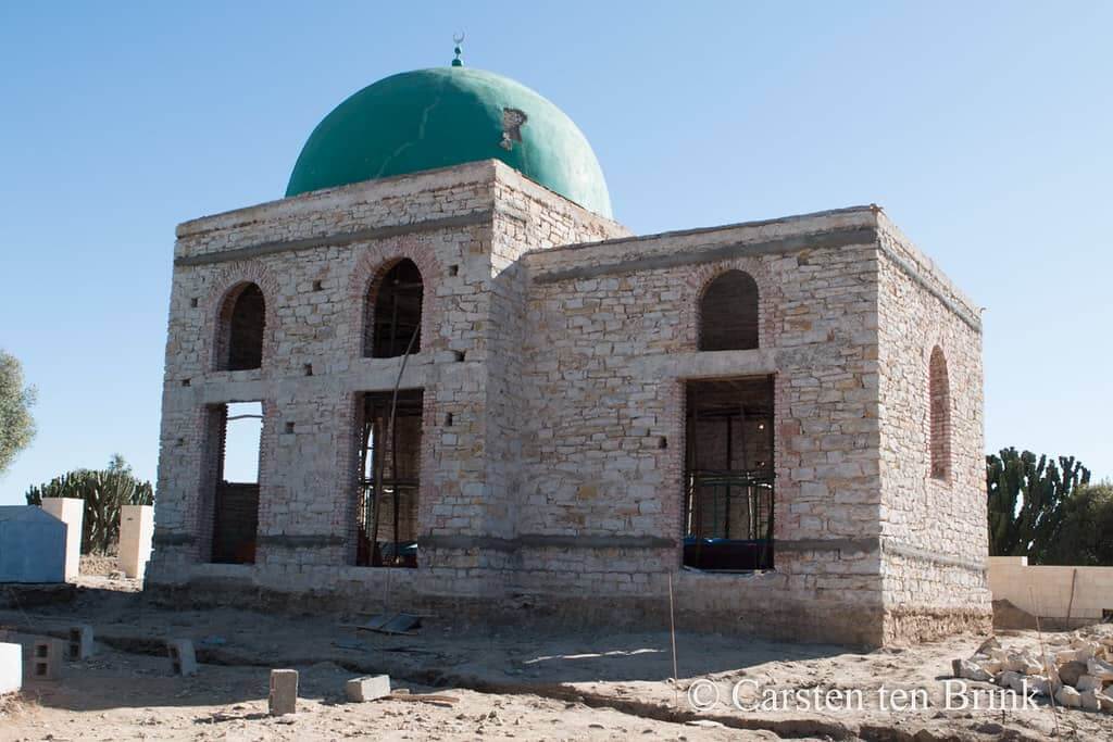 A mosque under construction in the desert featuring the iconic architecture of Al Nejashi Mosque