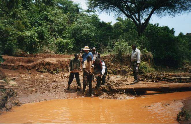 Gimbi, West Welega Zone, individuals gathered near a muddy stream, observing a log that lies across the water.