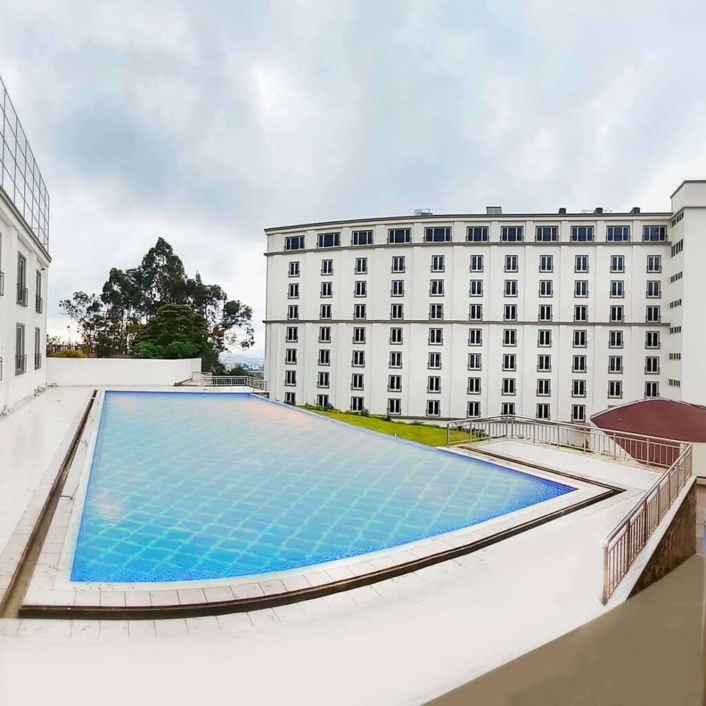 A serene pool in front of Haile Grand - Addis Ababa building, offering a breathtaking view of the sky.