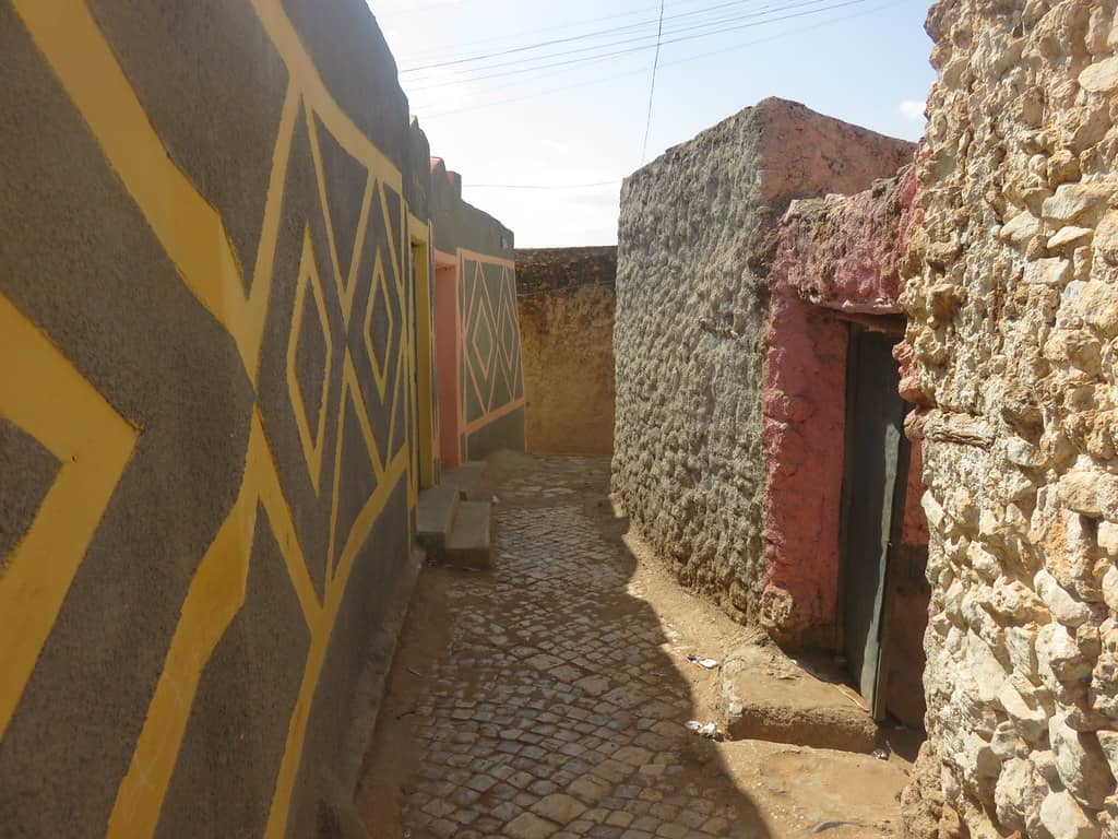 A narrow alley in Harar Jugol with a vibrant yellow and black painted wall.