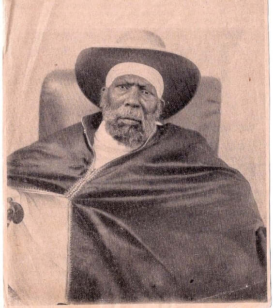 Vintage portrait of Emperor Menelik II wearing a hat and cape.