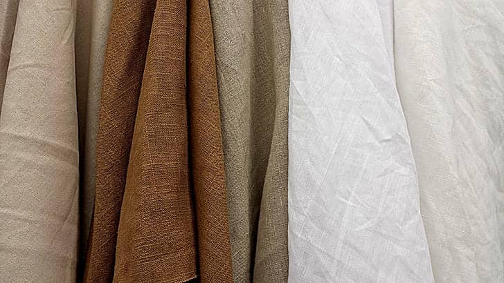 A vibrant assortment of linen fabrics in various colors neatly arranged in a row.